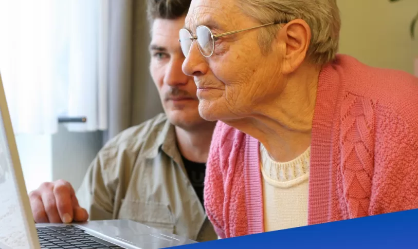 Ouder persoon die geholpen wordt door jonger persoon op laptop met het logo van Europass